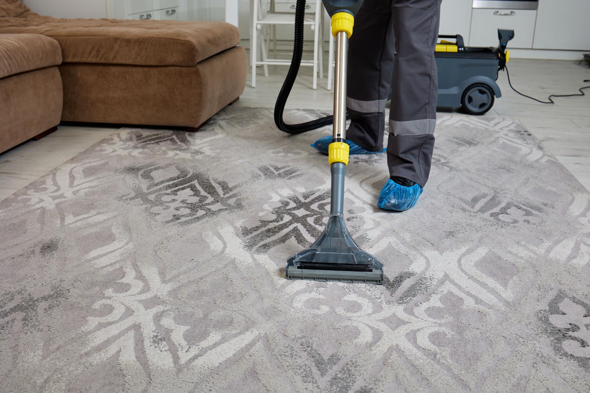 york pa Cleaning agency worker in overalls operates vacuum on living room carpet